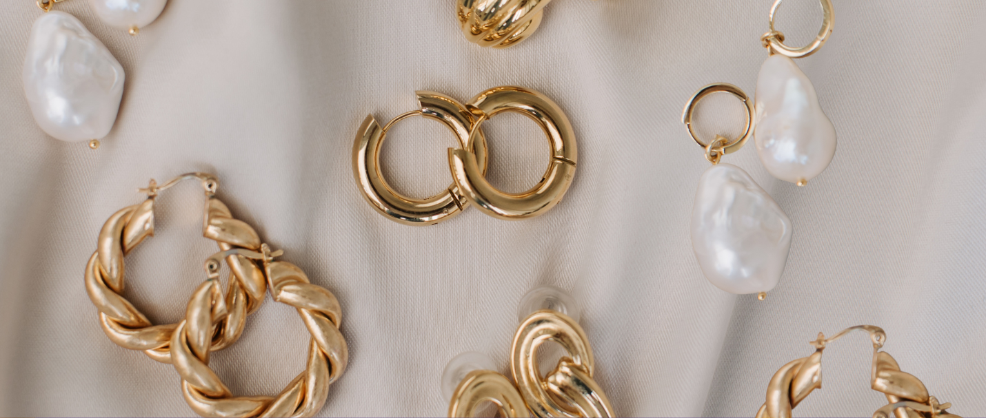 Gold earrings on a silk sheet