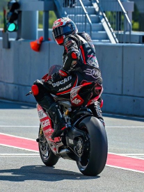 A professional motorcyclist wearing a Mass Sports custom suit in black and red as he rides in an arena